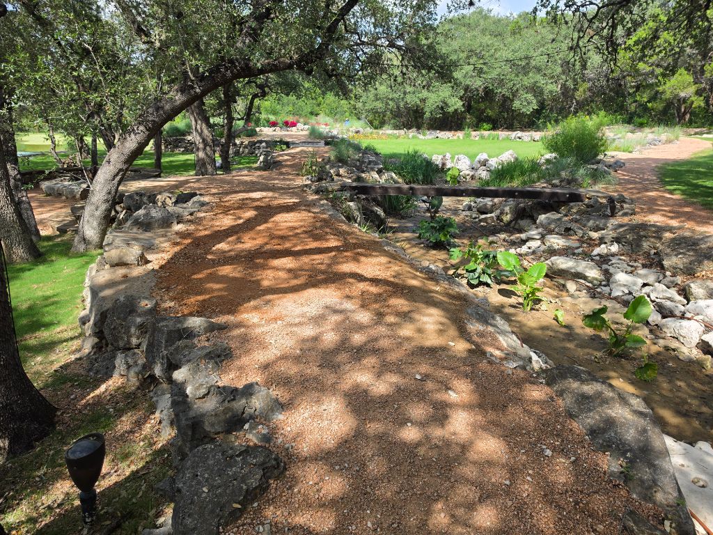 Pond Renovation After – Finished gravel path with rock borders and lush landscaping